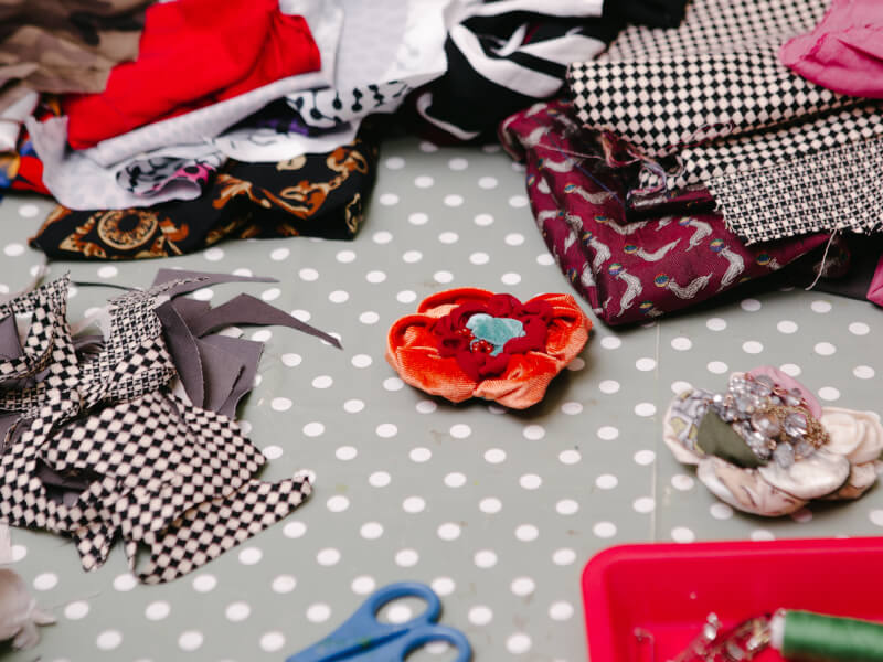 Fabric cuts and fabric flowers laid out on a spotted tablecloth
